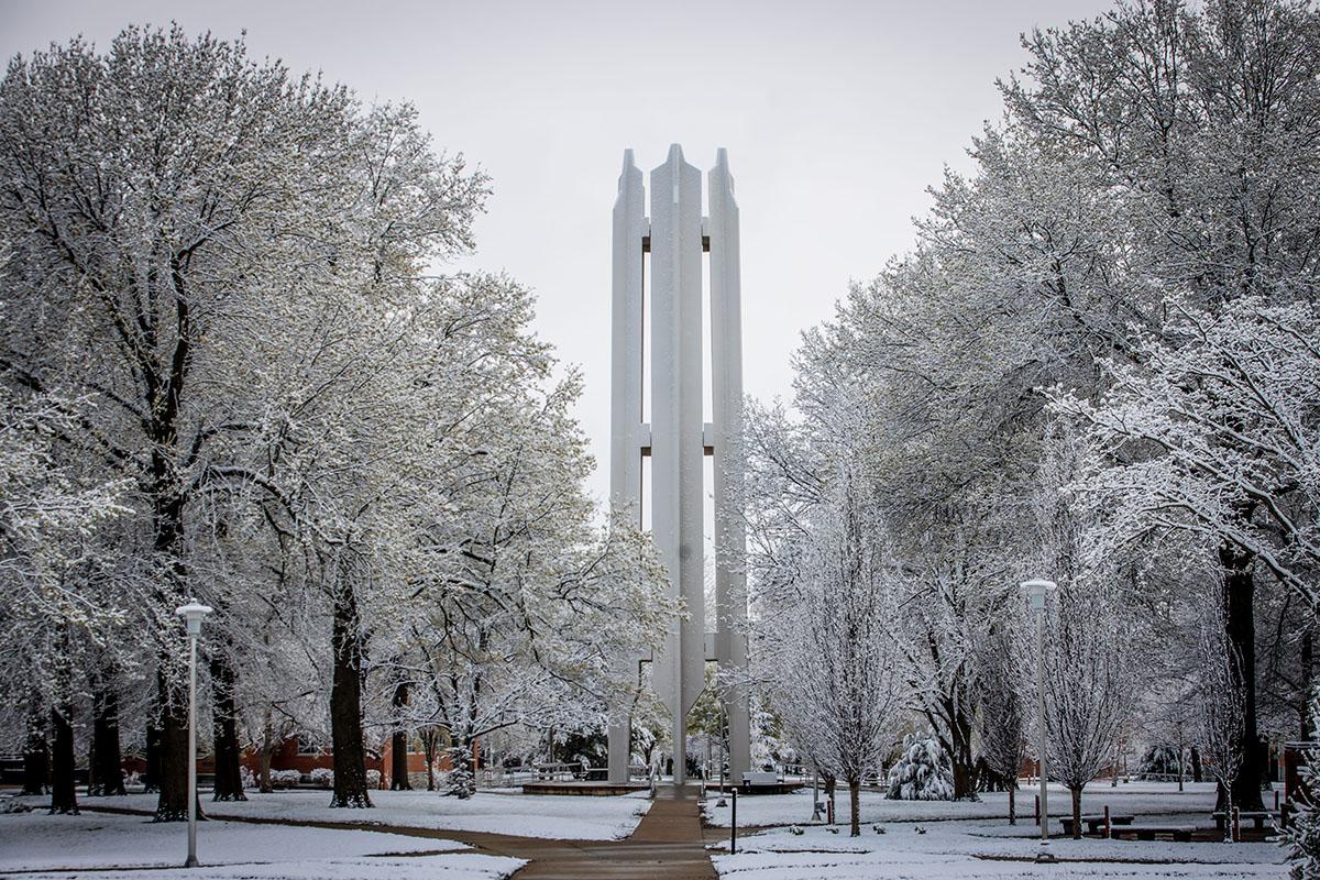 The Memorial Bell Tower is surrounded by snow-covered trees on a winter day.